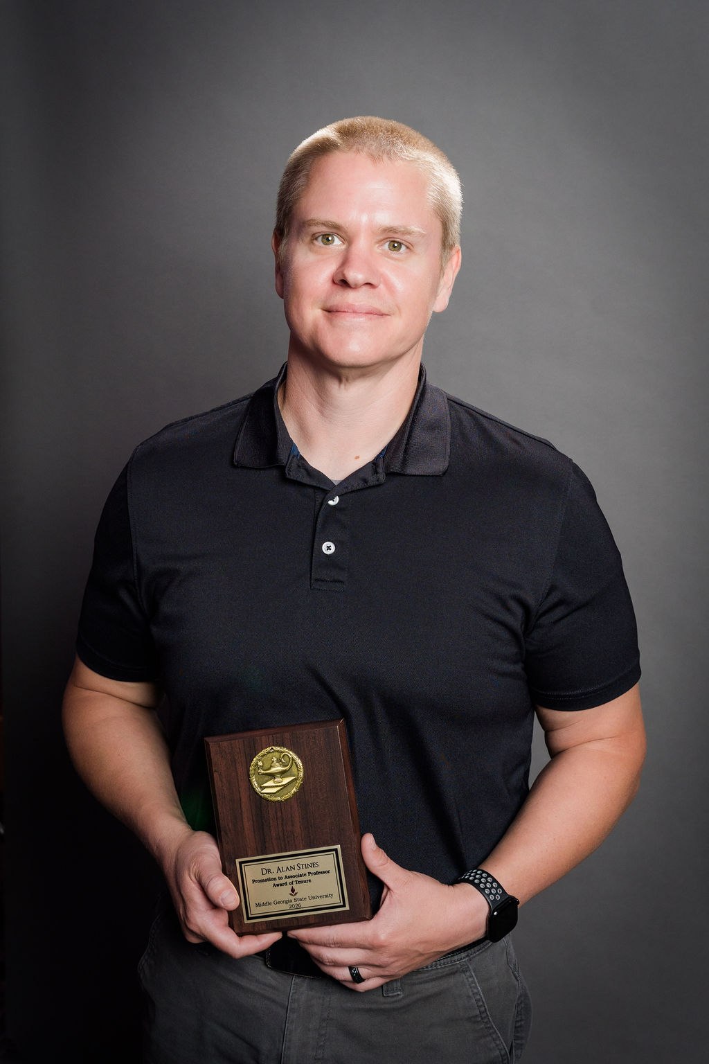 Alan Stines holding a teaching award plaque